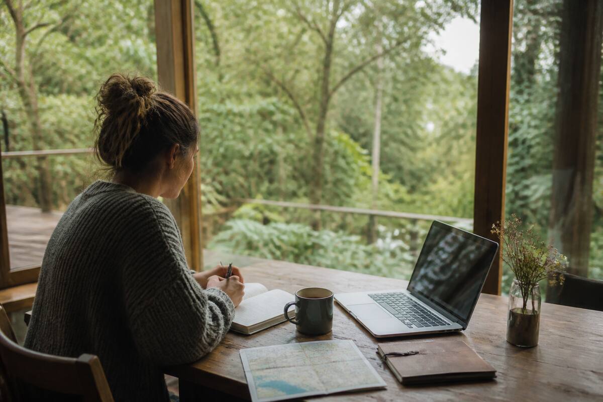 Reiziger vergelijkt vakanties en bestemmingen aan tafel met laptop en kaart