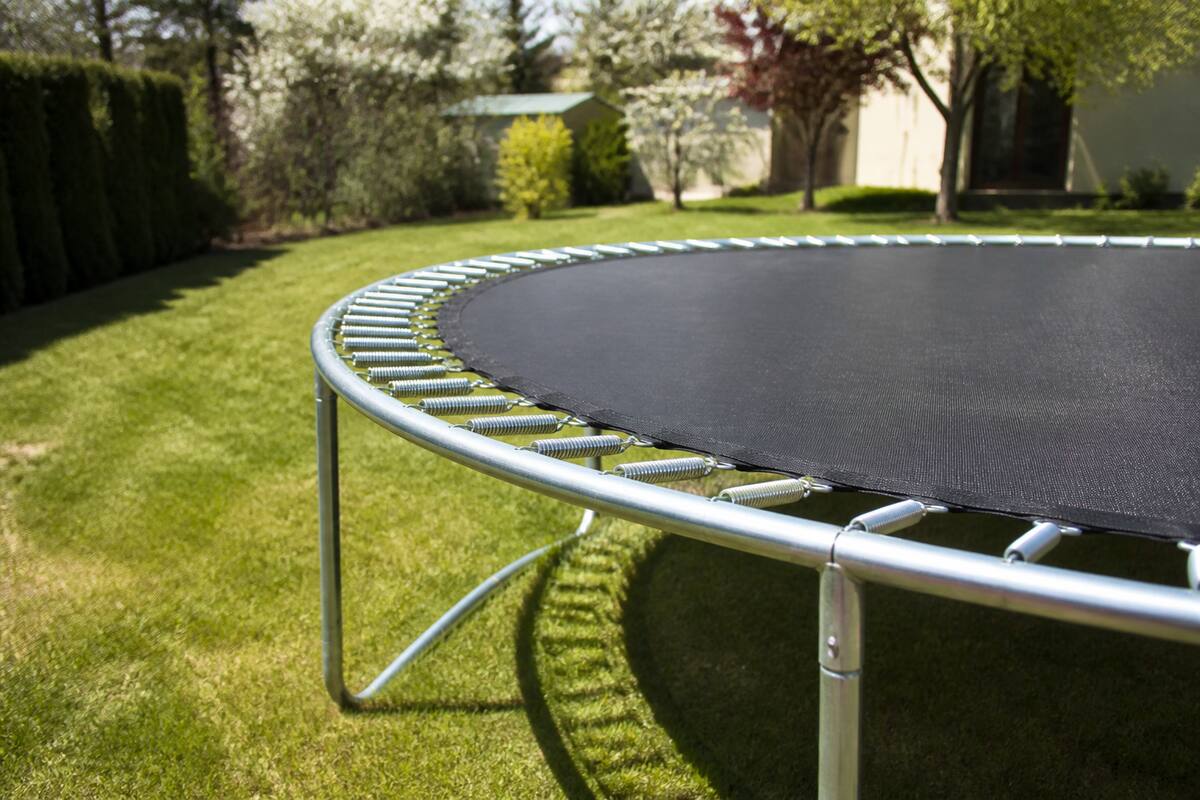 Trampoline in een tuin met focus op het frame en de springmat, klaar voor seizoensonderhoud