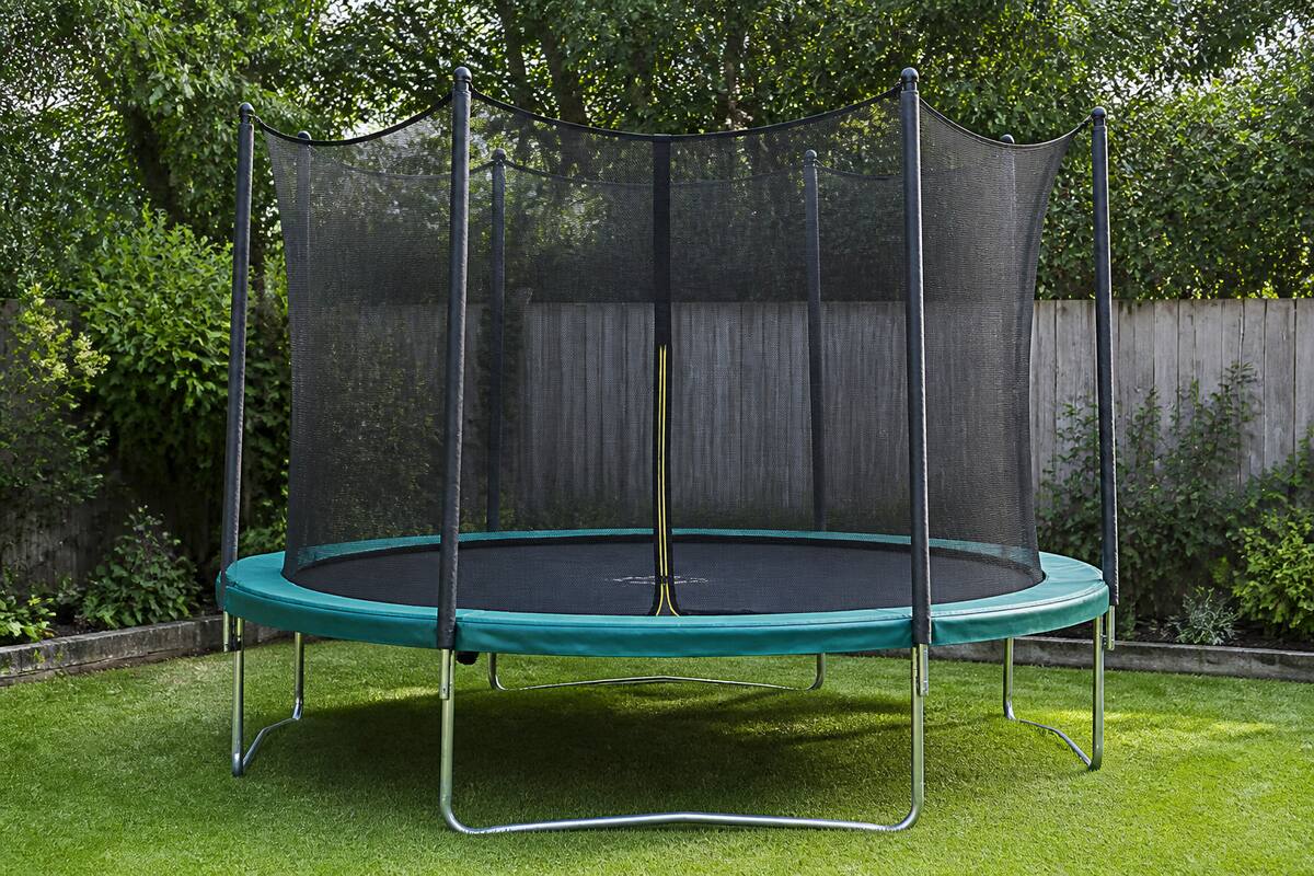 Trampoline op vlakke ondergrond in een tuin, met randkussen en veiligheidsnet